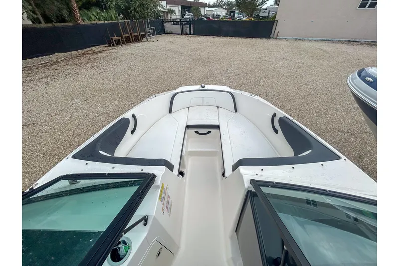 Slide: The Image of 2016 Searay 190 SPX boat interior with seating and windshield, parked on gravel. - 7