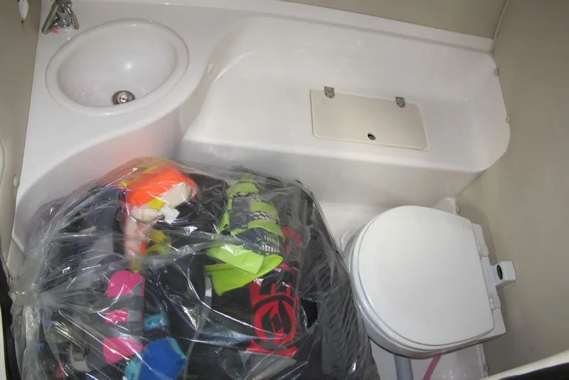 Slide: The Image of 2003 Chaparral 280 SSi boat bathroom with sink, toilet, and stored items in plastic bag. - 7