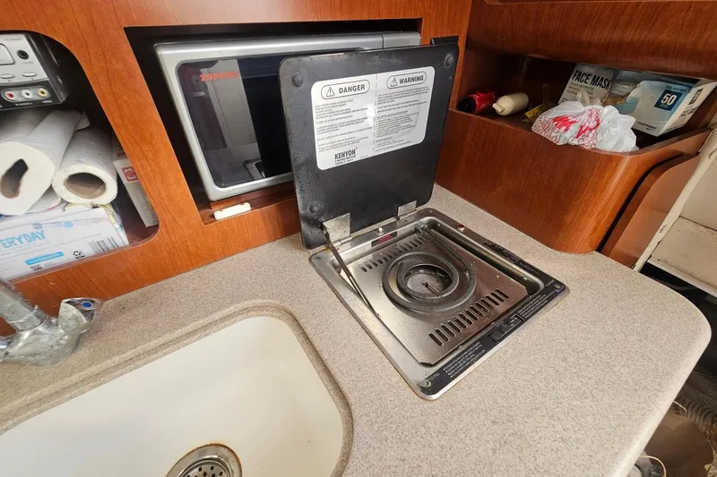 Slide: The Image of 2006 Pro-Line 32 Express boat kitchen with stove, sink, and storage shelves. - 10