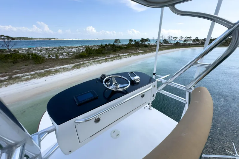 Slide: The Image of Custom Carolina Alex Willis Convertible 2000 boat helm overlooking serene coastal waters and sandy shoreline. - 24