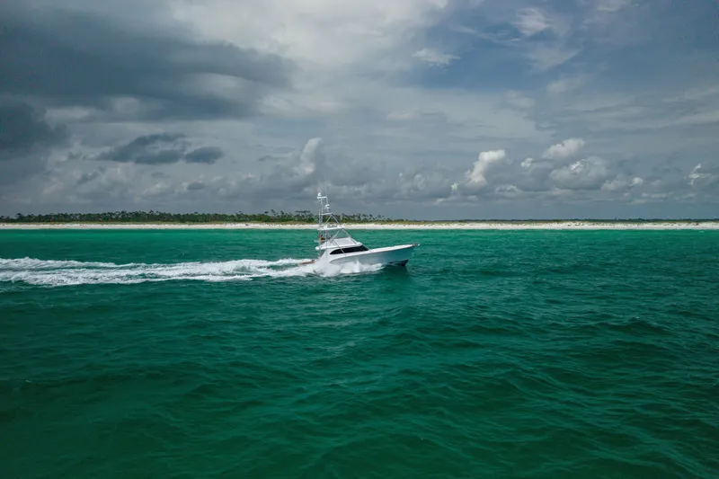 Slide: The Image of Custom Carolina Alex Willis Convertible 2000 cruising on turquoise ocean near sandy shoreline. - 32