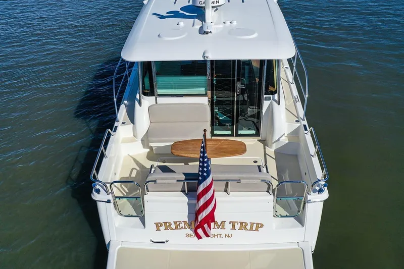 Slide: The Image of 2027 Sabre 38 Salon Express yacht with American flag, rear view on water. - 3
