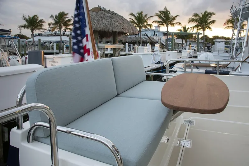 Slide: The Image of 2027 Sabre 38 Salon Express yacht with cushioned seating and wooden table, docked at marina. - 5