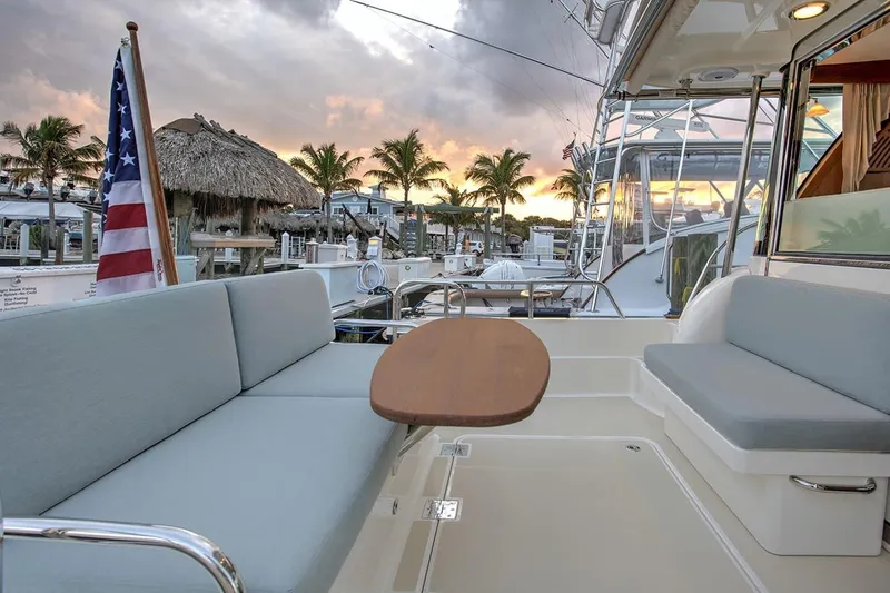 Slide: The Image of 2027 Sabre 38 Salon Express yacht deck with seating, table, and sunset view. - 6