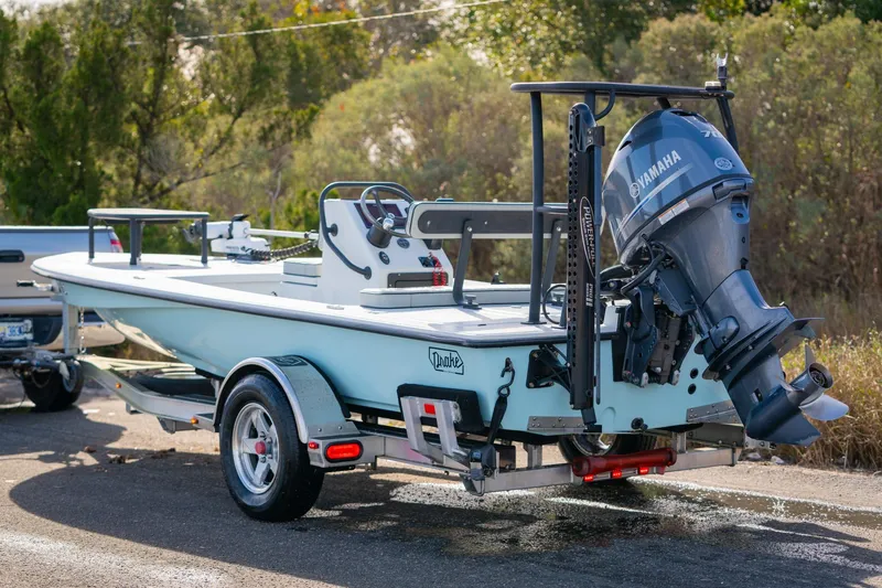 Slide: The Image of 2021 Drake Nomad boat on trailer with Yamaha outboard motor, parked outdoors. - 19