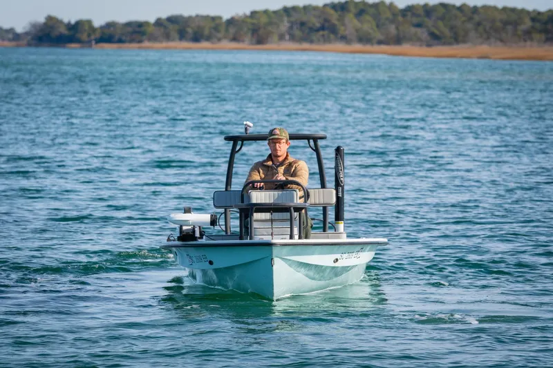 Slide: The Image of Man piloting 2021 Drake Nomad boat on a serene lake. - 2