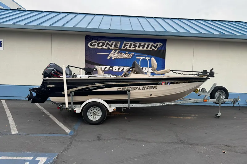 The Image of 2000 Crestliner 1650 Fish Hawk boat on trailer outside a fishing store. - 1