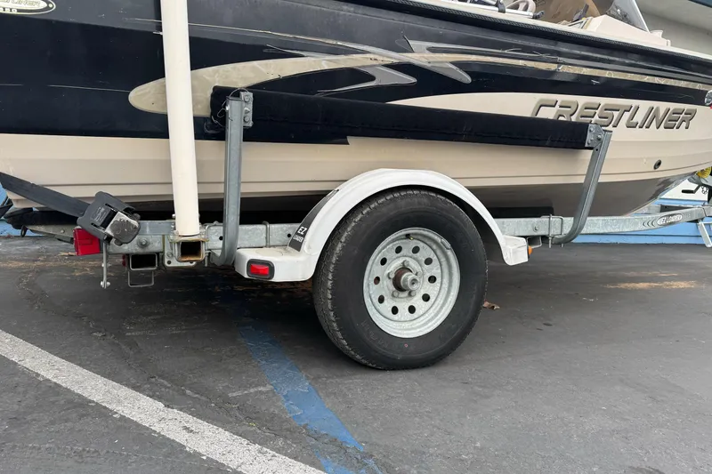 Slide: The Image of Trailer with 2000 Crestliner 1650 Fish Hawk boat parked on asphalt. - 2