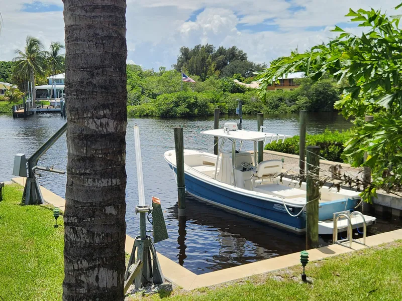 Slide: The Image of 2013 Panga Center Console boat docked by a lush riverside. - 2