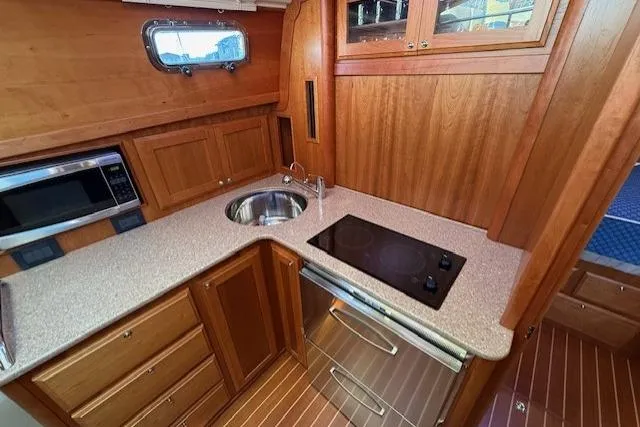 Slide: The Image of 2013 Sabre 38 Salon Express galley with wood cabinetry, sink, stove, and microwave. - 27