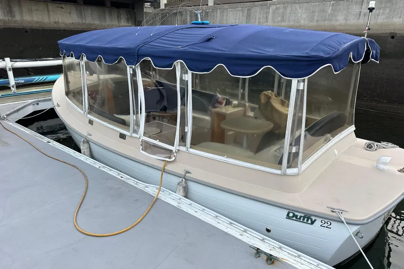 The Image of 2011 Duffy 22 boat docked, featuring blue canopy and clear side panels. - 0