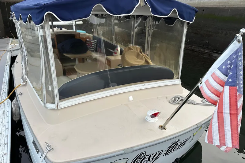 Slide: The Image of 2011 Duffy 22 boat with American flag, docked, featuring blue canopy and clear windows. - 2