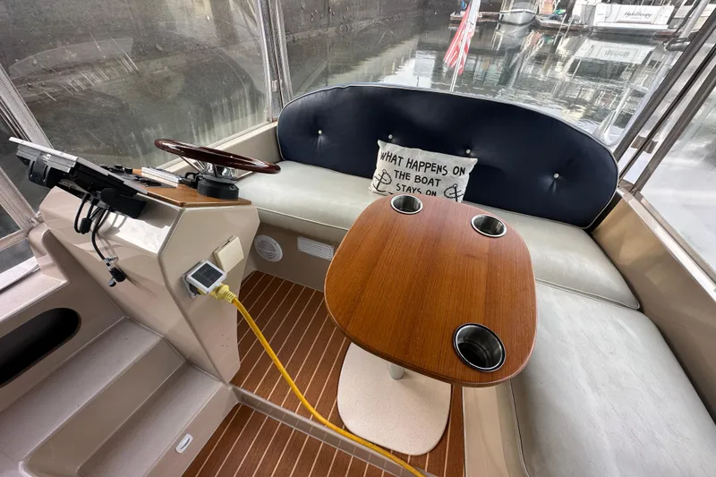Slide: The Image of Interior of a 2011 Duffy 22 boat with a wooden table and humorous pillow. - 4