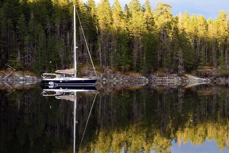 Slide: The Image of Jeanneau Sun Odyssey 45.2 sailboat reflecting on calm forested lake, 1999 model. - 2