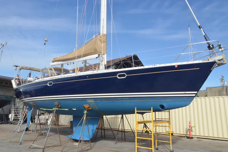 Slide: The Image of 1999 Jeanneau Sun Odyssey 45.2 sailboat on dry dock, blue hull, tan sails, clear sky. - 5