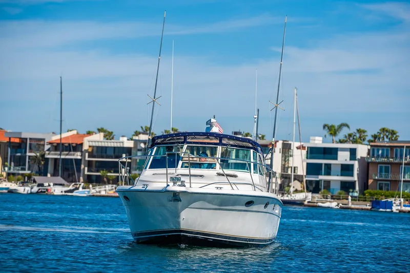 Slide: The Image of 2000 Tiara 31 Open yacht cruising in a marina with modern waterfront homes. - 3