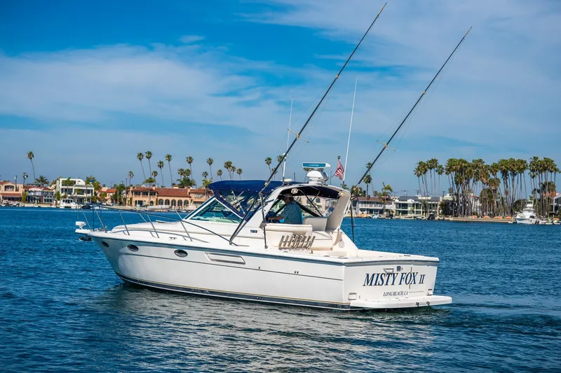 Slide: The Image of 2000 Tiara 31 Open boat cruising near palm-lined shore under blue sky. - 33