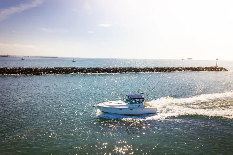 Slide: The Image of 2000 Tiara 31 Open boat cruising near a rocky breakwater on a sunny day. - 37