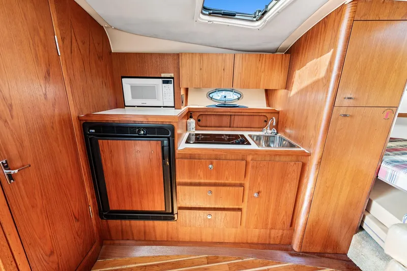 Slide: The Image of Compact galley kitchen in 2000 Tiara 31 Open boat with wood cabinetry and modern appliances. - 6
