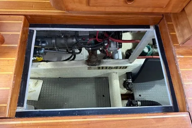 Slide: The Image of Engine compartment of a 2001 Sabreline Sedan boat, showcasing mechanical components and wooden flooring. - 56