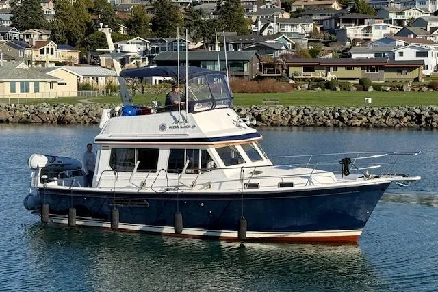 The Image of 2001 Sabreline Sedan boat cruising near a residential shoreline. - 0