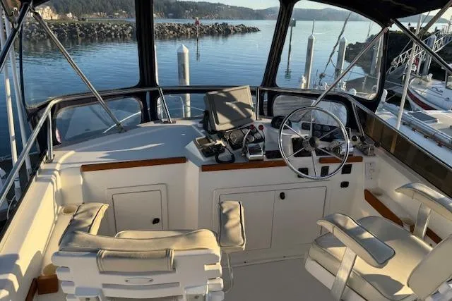 Slide: The Image of 2001 Sabreline Sedan boat cockpit with steering wheel, controls, and seating, docked by calm waters. - 1