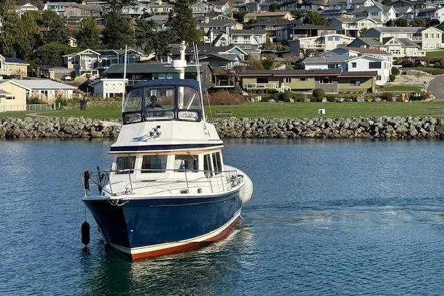 Slide: The Image of 2001 Sabreline Sedan boat cruising near a coastal residential area. - 14