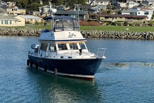 Slide: The Image of 2001 Sabreline Sedan boat cruising in a scenic coastal area. - 15