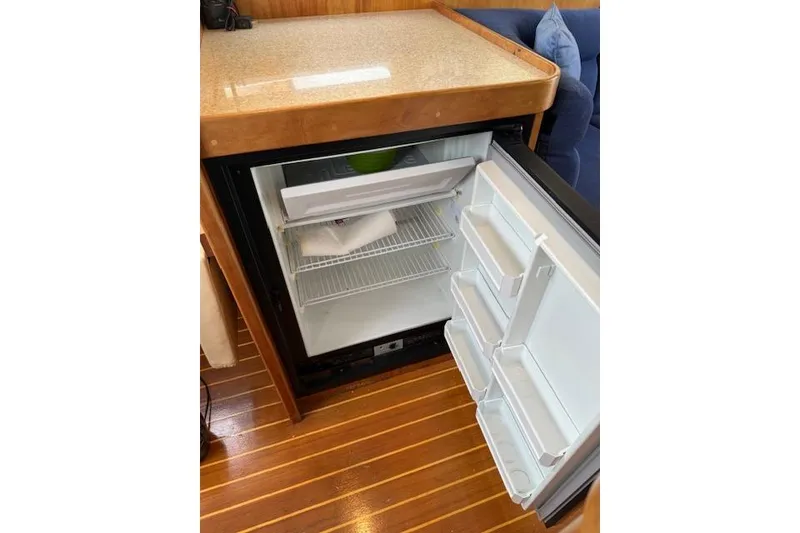 Slide: The Image of Open mini fridge in 2001 Sabreline Sedan, wooden floor, countertop above. - 34