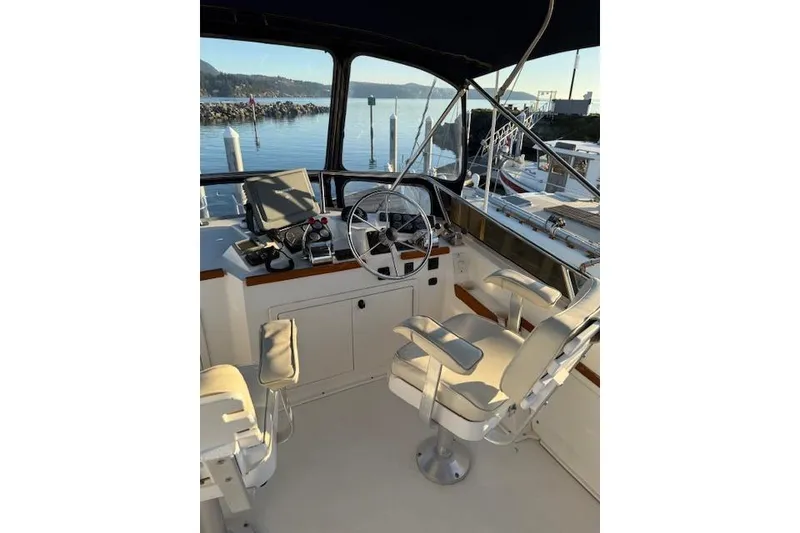 Slide: The Image of 2001 Sabreline Sedan boat cockpit with steering wheel and seating, docked by calm waters. - 41
