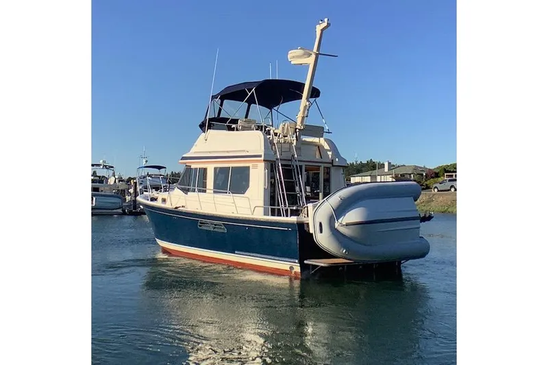 Slide: The Image of 2001 Sabreline Sedan boat with blue hull and inflatable dinghy, docked in calm waters. - 5