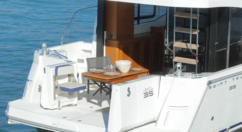 Slide: The Image of 2021 Beneteau Swift Trawler 35 with outdoor deck and table on water. - 3