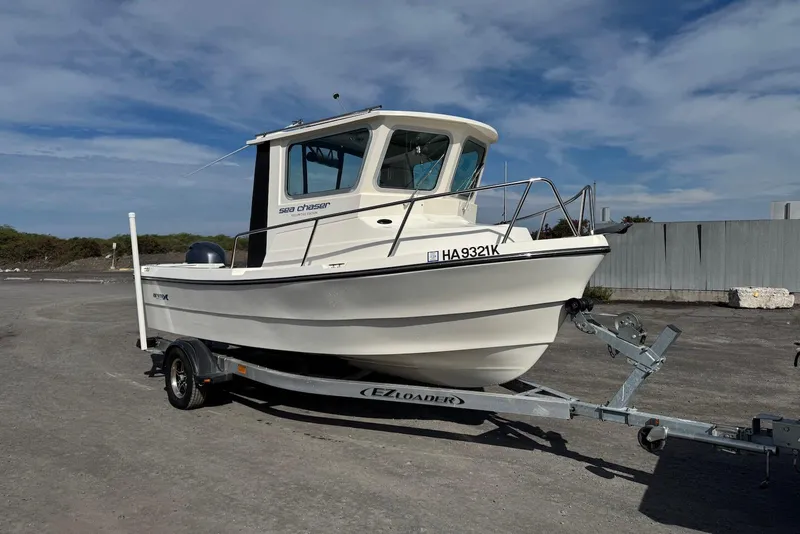 Slide: The Image of 2024 Arima Sea Chaser 19 Yellowtail Edition boat on trailer, parked outdoors. - 13