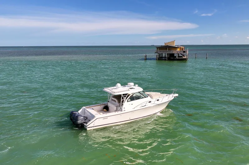 Slide: The Image of 2016 Pursuit OS 385 Offshore boat on turquoise water near a stilt house. - 15