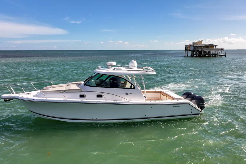 Slide: The Image of 2016 Pursuit OS 385 Offshore boat cruising on turquoise waters near a coastal structure. - 21