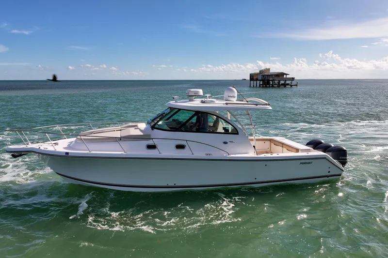 Slide: The Image of 2016 Pursuit OS 385 Offshore boat cruising on open water, with a distant structure. - 22