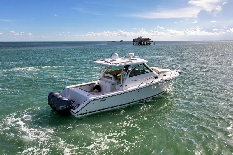 Slide: The Image of 2016 Pursuit OS 385 Offshore boat cruising on open water under a clear blue sky. - 31
