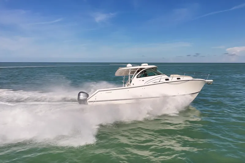 Slide: The Image of 2016 Pursuit OS 385 Offshore boat speeding on open water under clear blue sky. - 33