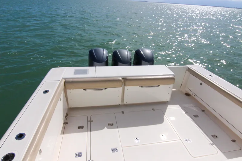 Slide: The Image of 2016 Pursuit OS 385 Offshore boat deck with triple outboard motors on open water. - 36
