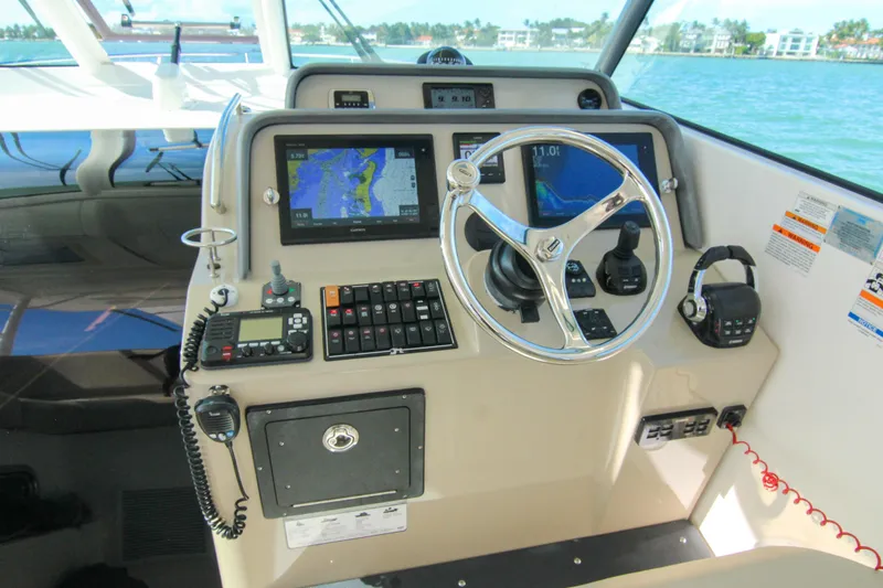 Slide: The Image of 2016 Pursuit OS 385 Offshore helm with navigation screens and controls, overlooking water. - 48