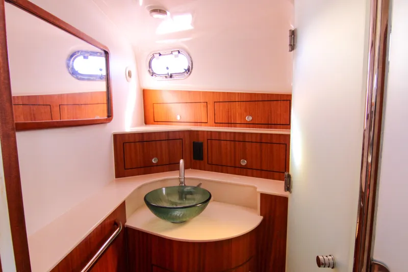 Slide: The Image of Luxurious bathroom in 2016 Pursuit OS 385 Offshore boat with glass sink and wooden cabinetry. - 57
