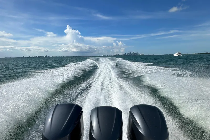 Slide: The Image of 2016 Pursuit OS 385 Offshore boat cruising with city skyline in the background. - 61