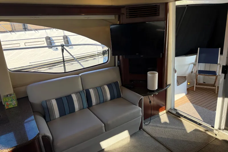 Slide: The Image of Interior of 2006 Sea Ray 44 Sedan Bridge yacht with sofa, TV, and deck access. - 12
