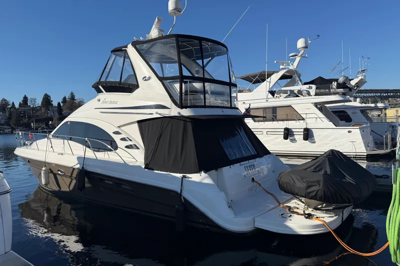 Slide: The Image of 2006 Sea Ray 44 Sedan Bridge yacht docked in marina under clear blue sky. - 2
