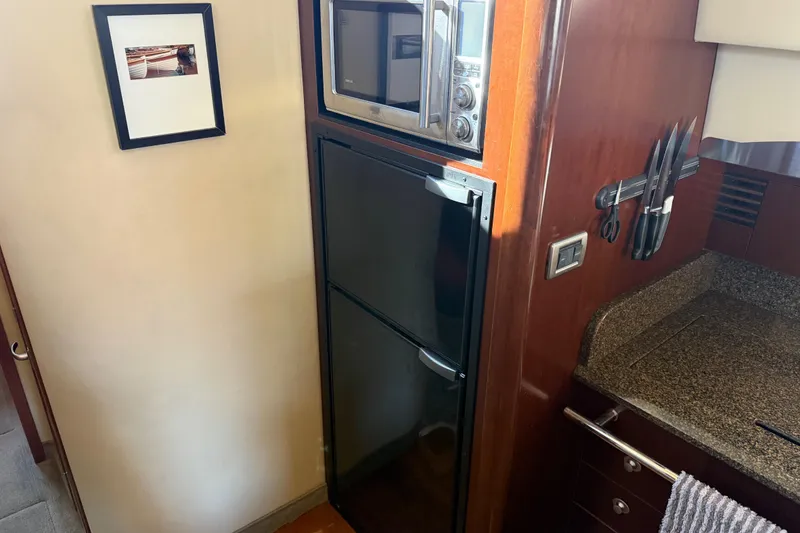 Slide: The Image of 2006 Sea Ray 44 Sedan Bridge kitchen with microwave, fridge, and knife set. - 26