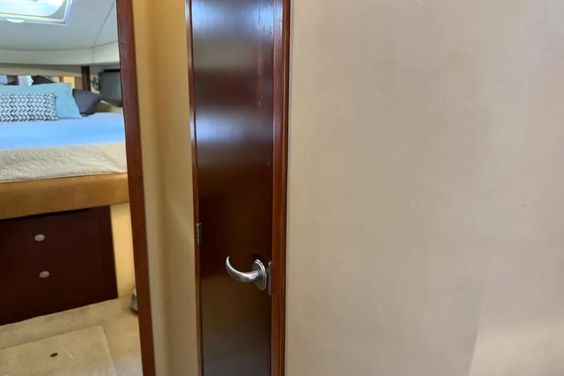 Slide: The Image of Interior view of 2006 Sea Ray 44 Sedan Bridge, featuring a bedroom and wooden door. - 32