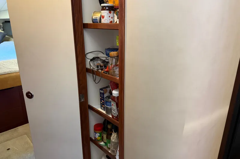 Slide: The Image of Pantry shelves inside 2006 Sea Ray 44 Sedan Bridge yacht, stocked with various food items. - 33