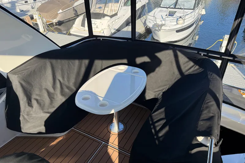 Slide: The Image of 2006 Sea Ray 44 Sedan Bridge yacht interior with table, covered seating, and marina view. - 75