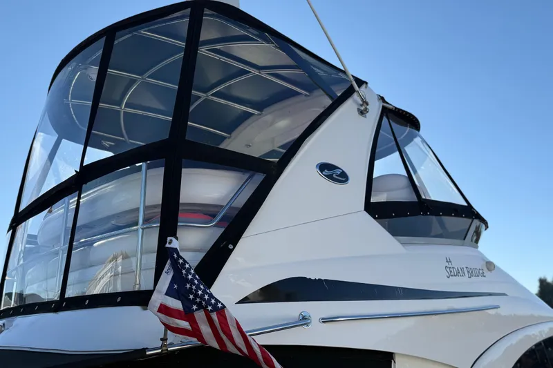 Slide: The Image of 2006 Sea Ray 44 Sedan Bridge yacht with American flag, clear blue sky background. - 97