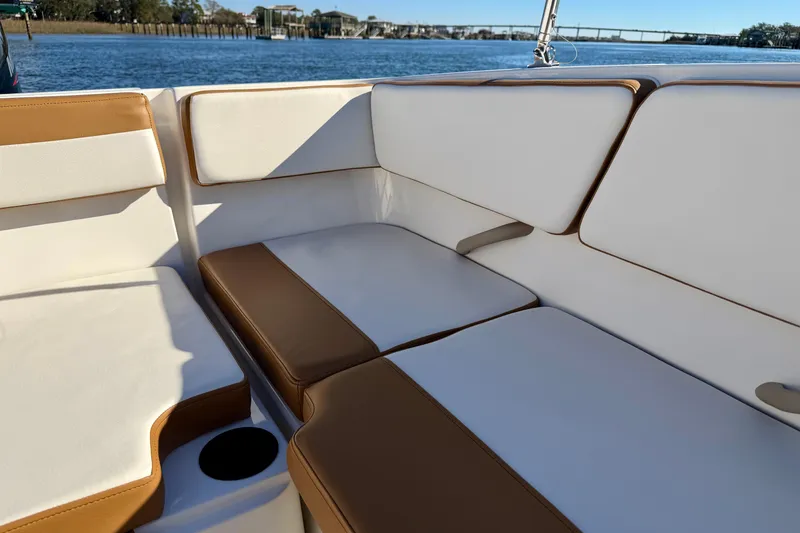 Slide: The Image of 2023 Bayliner VR4 Bowrider OB interior with tan and white seating, near water. - 18